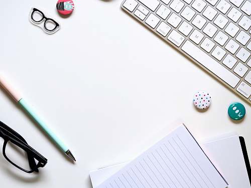 coffs harbour note paper, blue pen, and eyeglasses on white surface beside keyboard australia